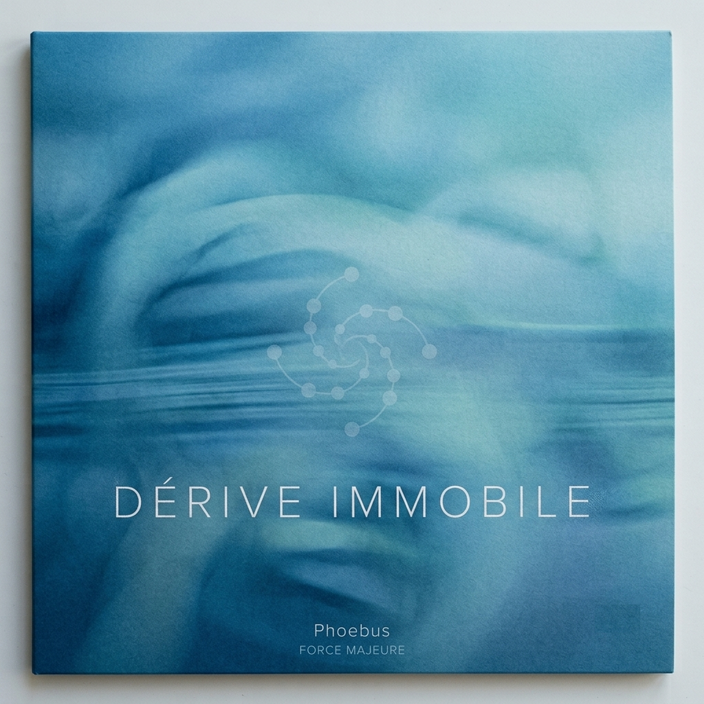 Pochette d'album carrée pour « Dérive Immobile », montrant une texture éthérée d'eau bleu-azur floue avec des vagues subtiles. Au centre, un glyphe graphique blanc minimaliste en forme de spirale géométrique et de constellations de points. En bas, le texte blanc indique « DÉRIVE IMMOBILE », suivi de « Phoebus » et « FORCE MAJEURE ».